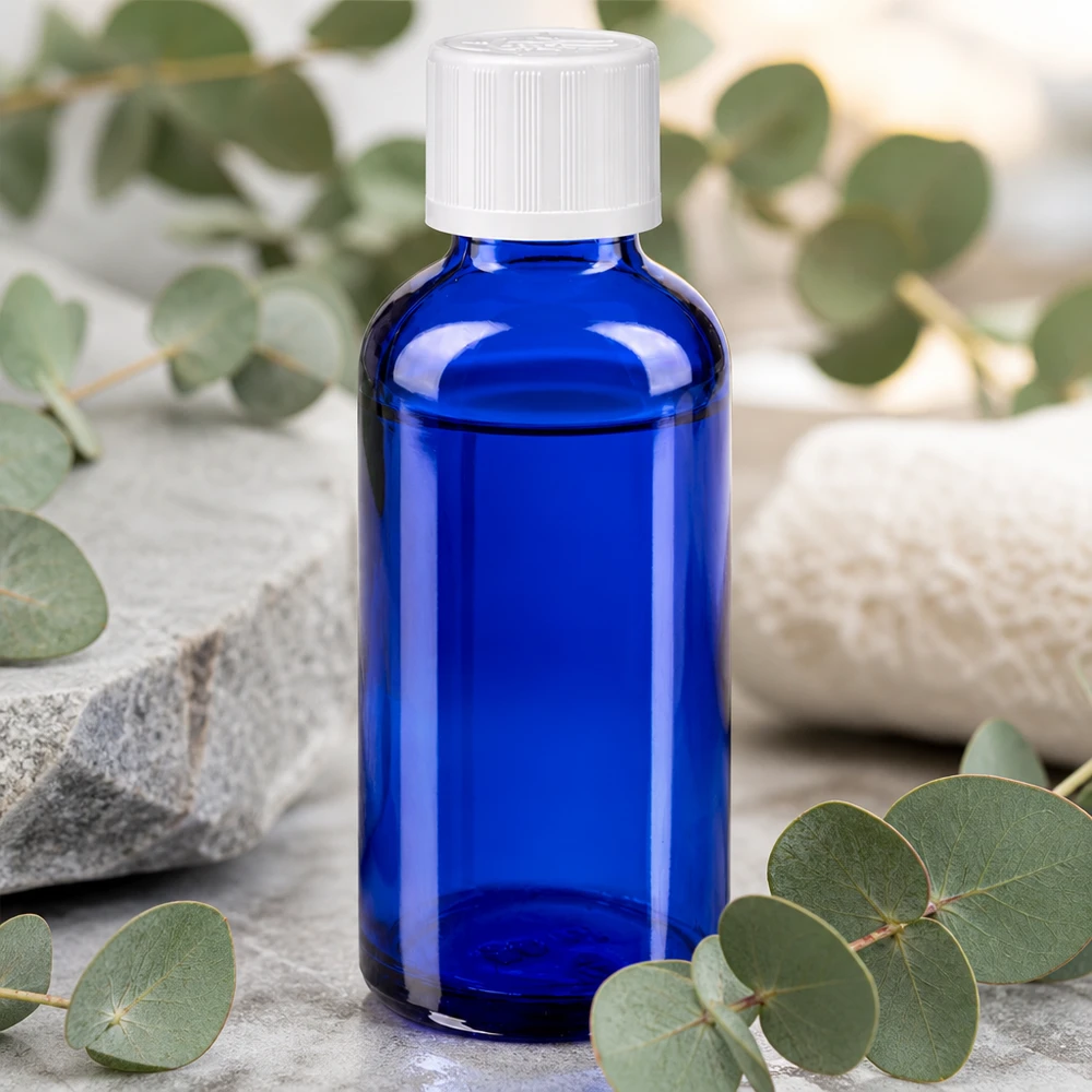 Apothekenflasche blau 50ml Tropfverschluss weiß Kindersicherung Standard 50ml blaue Apoglasflasche mit Tropfeinsatz auf grauem Stein im minimalistischen Spa-Arrangement
