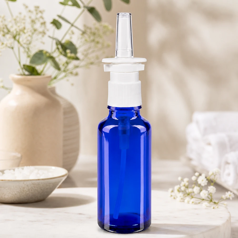 Apothekenflasche blau 30ml Nasenzerstäuber weiß Standard Seitenansicht blaue Pharmaflasche 30ml mit weißem Nasalsprayer auf hellem Marmoruntergrund