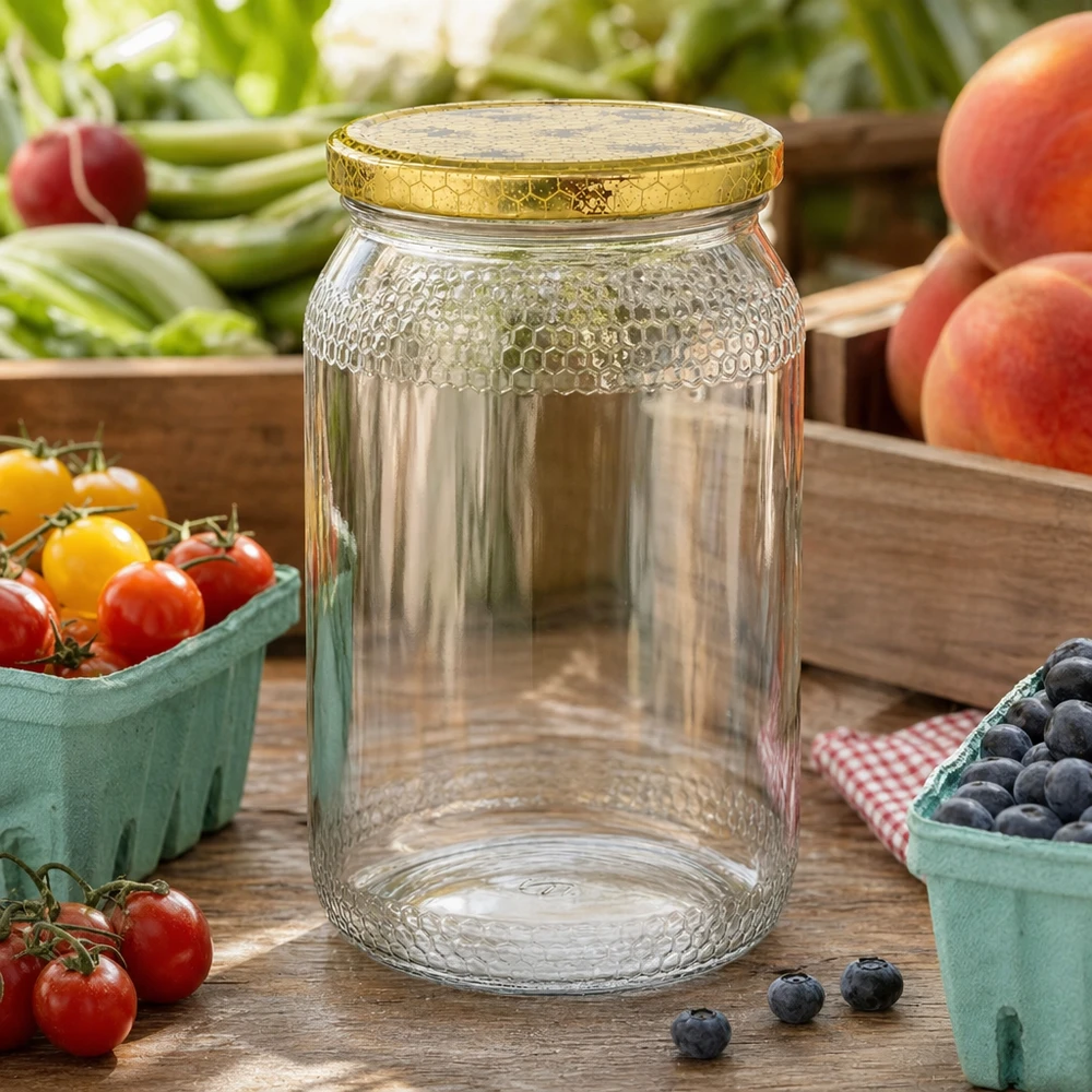 900ml Honigglas leer mit goldenem Bienenwaben-Deckel zwischen frischem Obst und Gemüse auf Holztisch Küche
