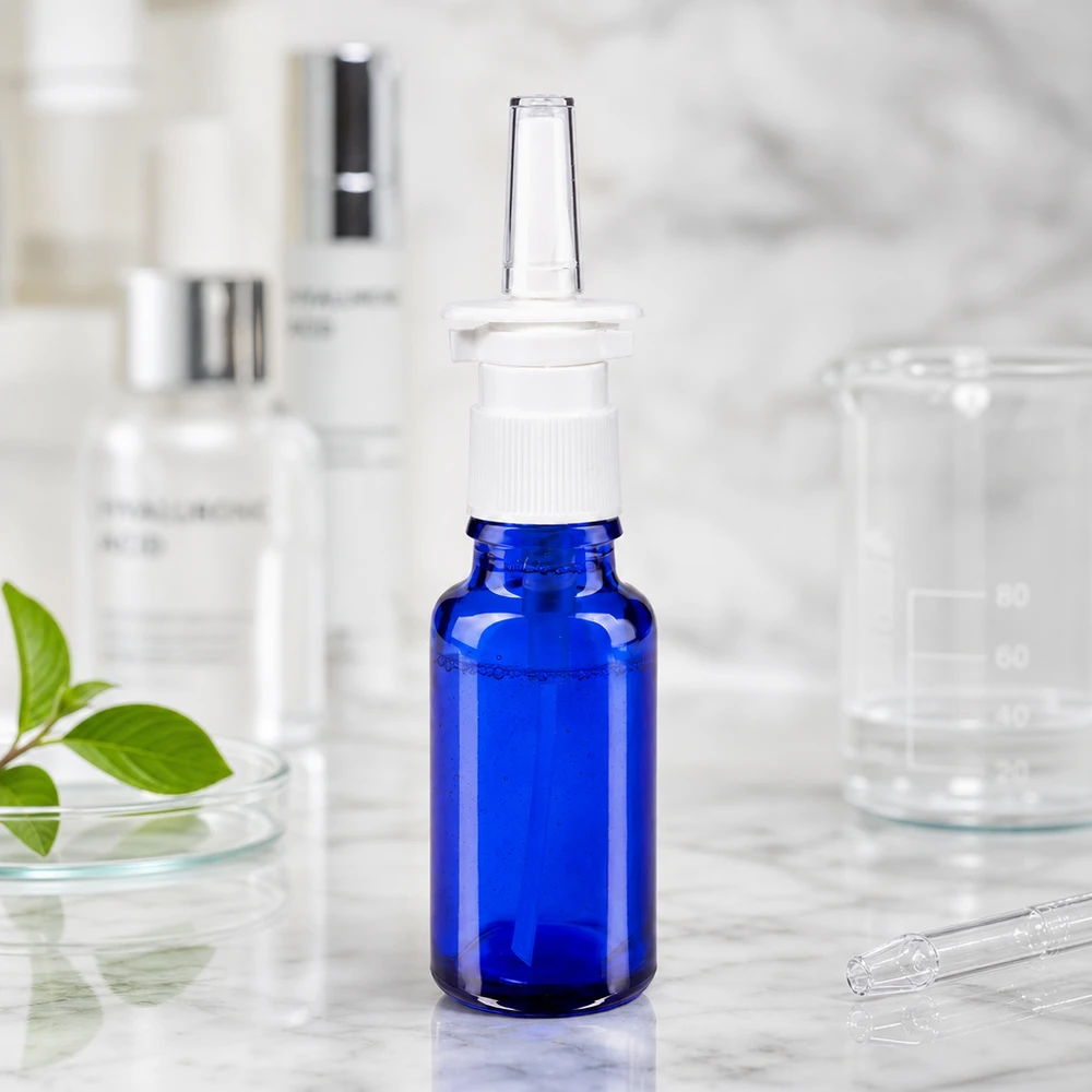 Arzneimittelflasche 20ml in Blauglas mit Nasenzerstäuber und transparentem Applikator auf Marmorfläche