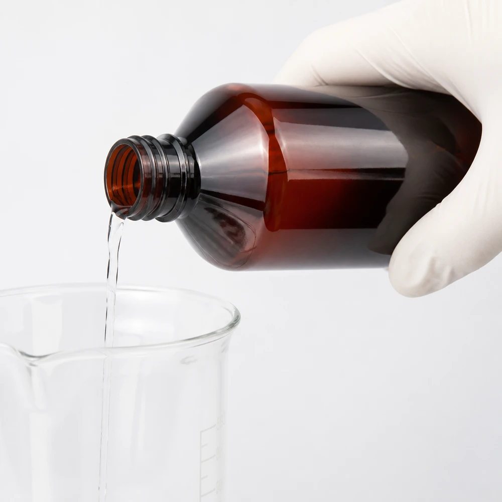 Braune Kunststoffflasche 1000ml mit weißem OV beim sicheren Ausgießen in Glasbecher