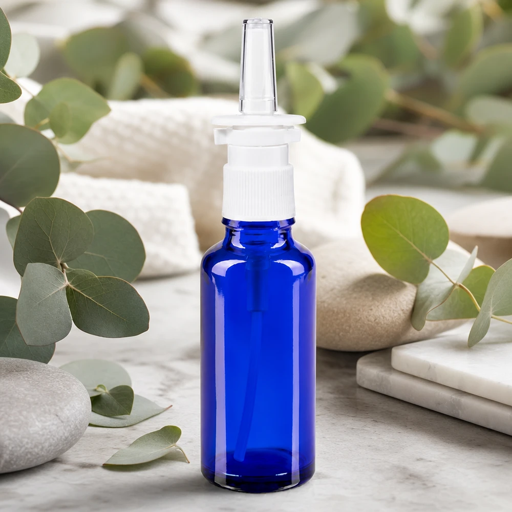 Apothekenflasche blau 30ml Nasenzerstäuber weiß Standard Blaue Apothekerglasflasche 30ml mit Nasenspraykopf umgeben von frischen Eukalyptusblättern