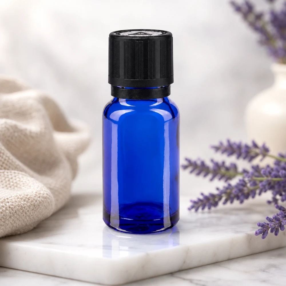 Apothekenflasche blau 10ml Tropfer Giessring 1mm schwarz Kindersicherung Blindenwarnsymbol Originalitätsverschluss Blaue Tropfflasche 10ml mit OV-Sicherheitsverschluss vor Lavendelzweigen und weißem Keramikgefäß