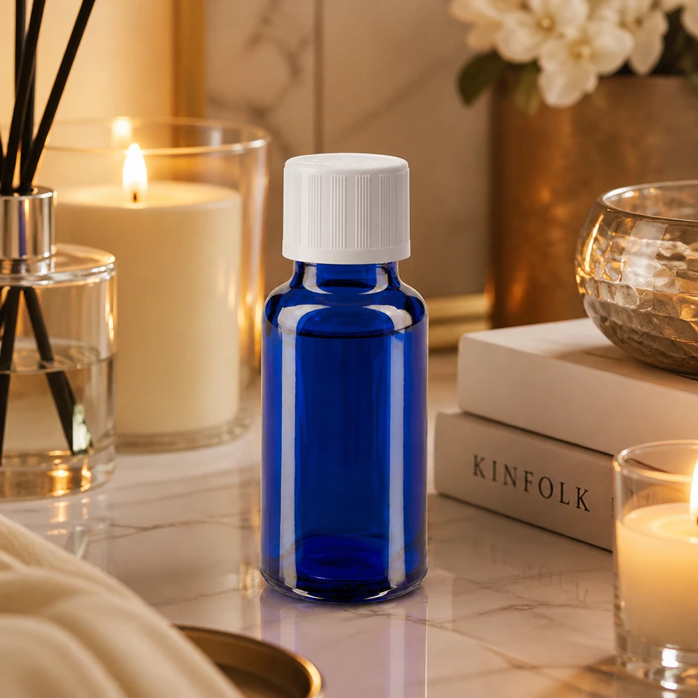 Blaue Phiole 20ml mit weißem Schraubverschluss auf Marmoroberfläche mit Kerzenlicht