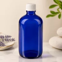 Blaue Medizinflasche 100ml mit geripptem weißem Verschluss vor hellem Hintergrund