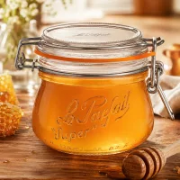 250ml Le Parfait Super Vorratsglas mit Bügelverschluss gefüllt mit Honig auf Holzbrett mit Honiglöffel