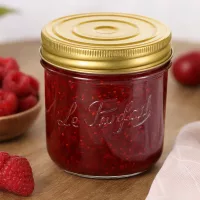 415ml Sturzglas Familia Wiss mit goldenem Deckel gefüllt mit roter Marmelade neben frischen Erdbeeren auf Holztisch