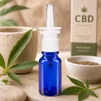 10ml Nasensprayflasche aus blauem Schutzglas neben Hanfsamen und Natursteinen