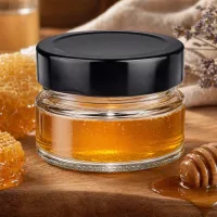 80ml Rundglas mit schwarzem BasicSeal Deckel gefüllt mit Honig Bienenwaben Holzlöffel natürliche Küchenszene