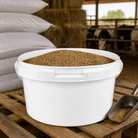 Weißer offener PP-Behälter 3,5L mit Tierpellets im Rinderstall auf Holzpalette