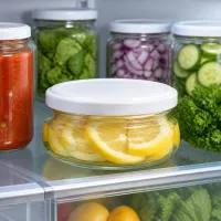 Terrinenglas UNiTWIST 120ml mit weißem Deckel neben Salsa Zwiebeln und Gurken im Kühlschrank