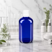 Pharmazeutische 100ml Blauglasflasche mit OV-Verschluss weiß zwischen Laborgeräten und Naturpflanzen