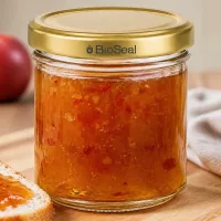 BioSeal 200g Glas mit Aprikosenmarmelade gefüllt goldener Deckel auf Holztisch mit Toast und Obst im Hintergrund