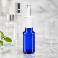 Arzneimittelflasche 20ml in Blauglas mit Nasenzerstäuber und transparentem Applikator auf Marmorfläche