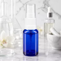 Transparente Sicherheitskappe auf blauer 10ml Apothekerflasche mit weißem Pumpmechanismus Nahaufnahme