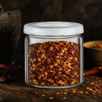 Aufbewahrungsglas aus klarem Glas mit grob gemahlenen Chiliflocken und weißem Schraubdeckel