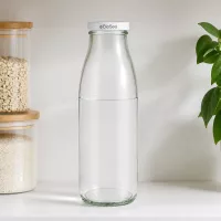 500ml Glasflasche mit BioSeal Verschluss in Küchenumgebung, neben Vorratsgläsern mit Müsli und grüner Pflanze