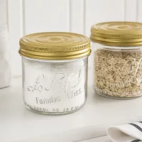 539ml Sturzglas Familia Wiss mit goldenem Deckel und Einmachglas mit Getreide auf weißer Oberfläche