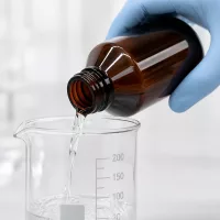 Braune 200ml Enghalsflasche aus PET beim kontrollierten Ausgießen im Reinraum