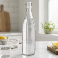 500ml UNiTWIST Glasflasche mit Sprudelwasser befüllt auf Marmortheke in moderner weißer Küche mit Zitrone