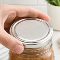 TO100 Deckel silber matt 100mm wird mit einer Hand auf Vorratsglas in Küche platziert
