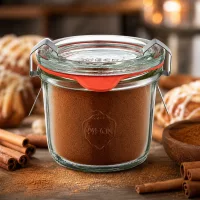 Mini Sturzglas 80ml mit Zimtpulver neben Holzschüssel mit Gewürz und Backwaren