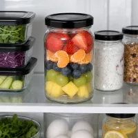 UNiTWIST Rundglas 110ml mit geschichtetem Obstsalat im Kühlschrank neben Vorratsgläsern mit schwarzem TO48 Deckel