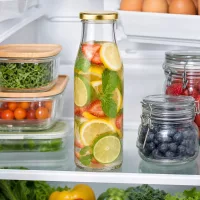 500ml Glasflasche BasicSeal gold gefüllt mit Früchtewasser Zitrone Erdbeere Minze im geöffneten Kühlschrank