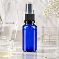 20ml blaues Apothekerglasfläschchen mit schwarzem Sprühaufsatz vor Laborhintergrund