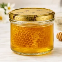 Gefülltes 250g Honigglas mit echter Bienenwabe und dekorativem Deckel zeigt goldenen Honig im Glas