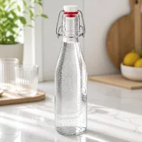250ml Glasflasche mit Bügelverschluss gefüllt mit Mineralwasser, moderne Küchenarbeitsplatte aus Marmor mit Gläsern