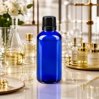 50ml blaues Apothekerglas mit 8mm Verschluss auf Marmor neben Erlenmeyer und Parfumflakons