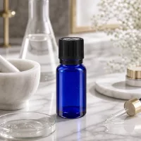 Kleine kobaltblaue Apo-Tropfflasche 10ml schwarzer Sicherheitsverschluss neben Glaskolben und Mörser