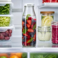 500ml Glasflasche mit BioSeal Deckel im Kühlschrank, gefüllt mit Beeren und Minze, neben Meal Prep Behältern