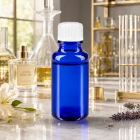 Blaue UV-Schutzflasche 20ml Glas mit weißem Standardverschluss neben Luxusparfüm