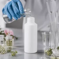 Befüllung einer weißen HDPE Apothekerflasche 30ml mit Handschuhen im Kosmetiklabor