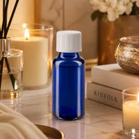 Blaue Phiole 20ml mit weißem Schraubverschluss auf Marmoroberfläche mit Kerzenlicht