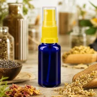 Handliche Sprühflasche blau 20ml mit gelbem Aufsatz neben Lavendel und Kamillenblüten